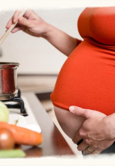 Schwangere Frau beim Kochen im Alltag – Ernährung zur Stärkung der Mitte vor der Geburt