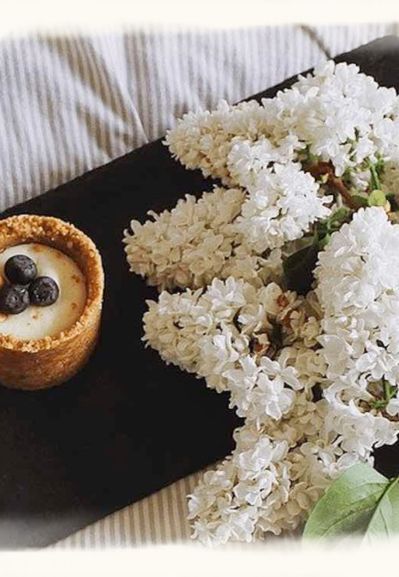 Ein kleines Törtchen im Bett mit Fliederblüten als Symbol für Wochenbettzeit und Geborgenheit