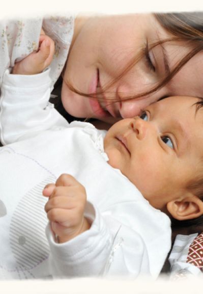 Frau hält ein Baby liebevoll im Arm – Symbol für Kinderwunsch und frühe Bindung